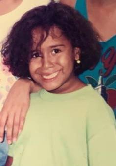 A smiling girl with curly hair in a green sweatshirt