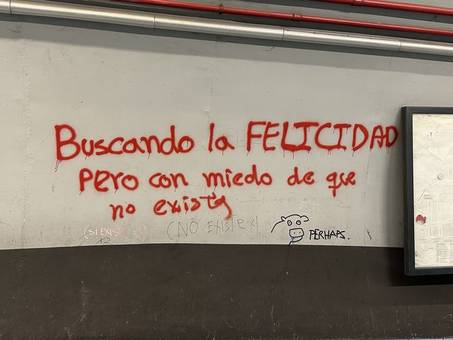 Red graffiti in Spanish about searching for happiness, with replies written underneath