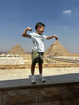 A boy flexing in front of the pyramids of Giza